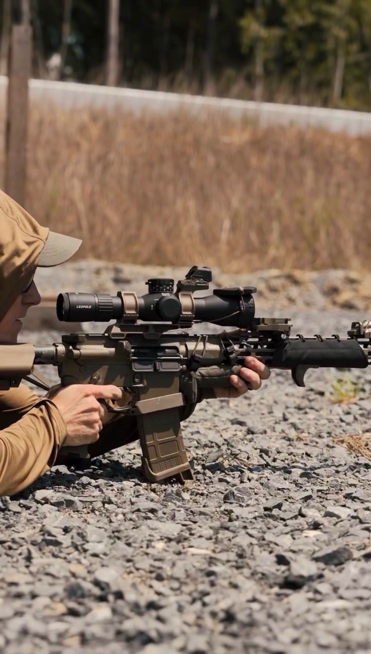 Person holding a rifle with scope in a natural setting